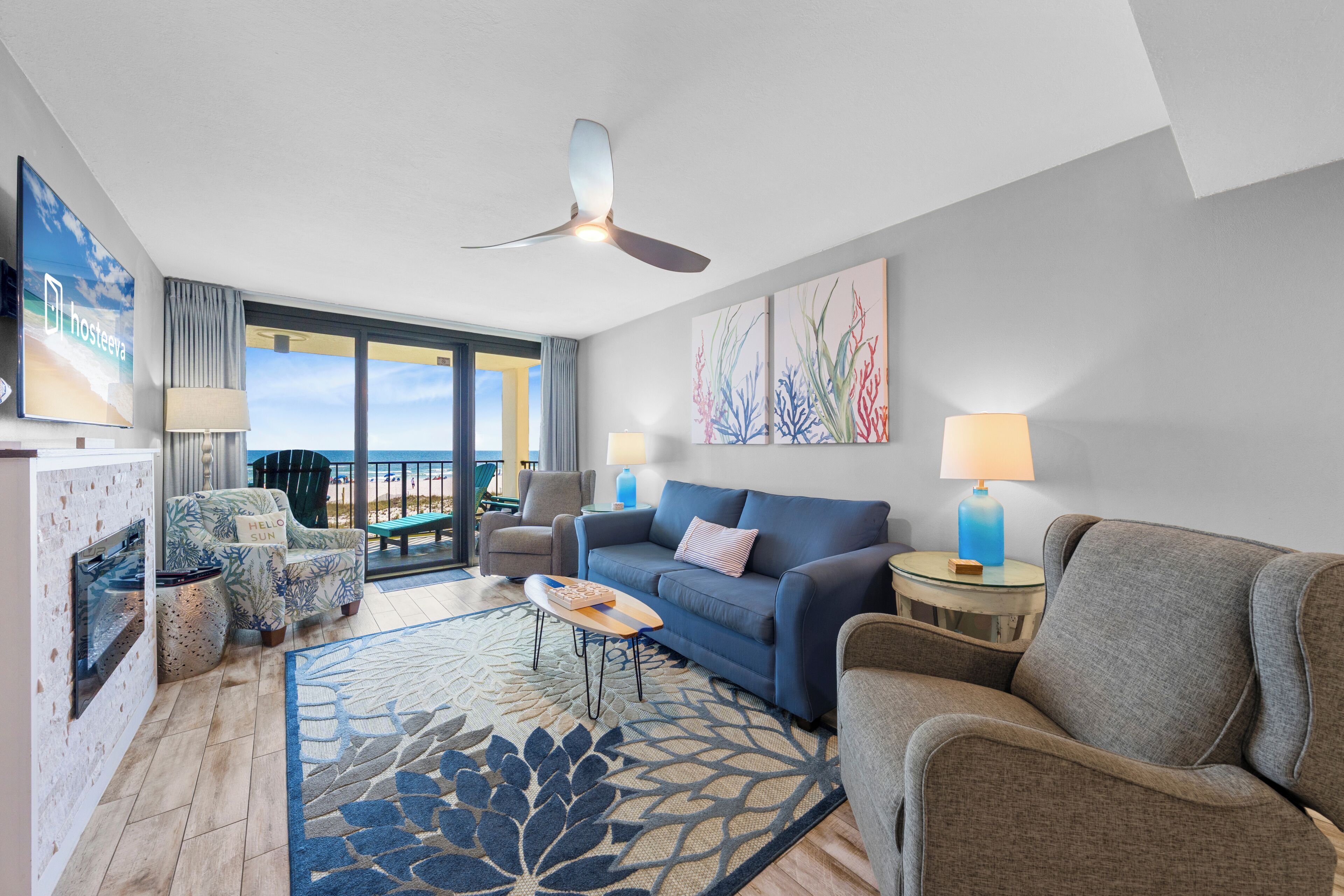 A modern living room with a sofa, chairs, a coffee table, a ceiling fan, and artwork on the walls.