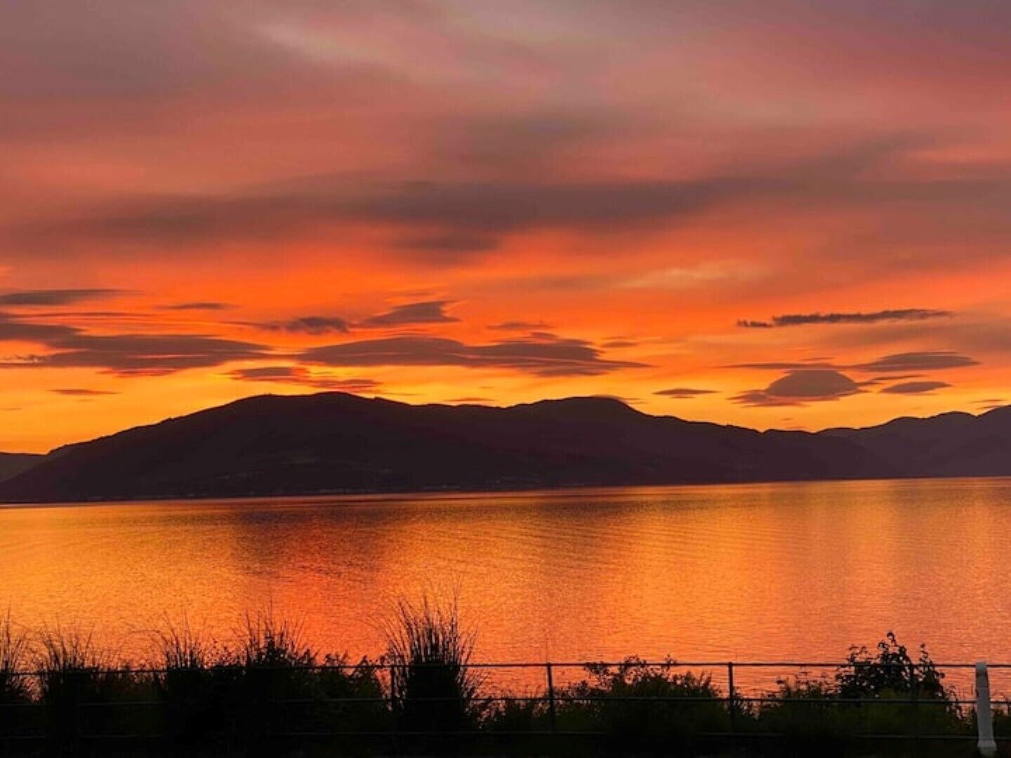 A sunset over a calm lake with mountains in the background.