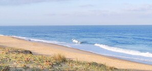 Een strand met een zandstrand en rustige golven.