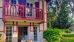 A two-story building with a balcony, a dining area with chairs and a table, and a well-maintained garden. - Villa ALICE ideally located in the heart of the MOLIETS-ET-MAA golf course (MOLIETS-ET-MAA)