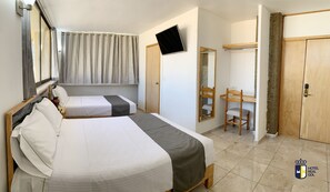 Habitación de hotel con dos camas, televisión, espejo, silla de madera y armario.