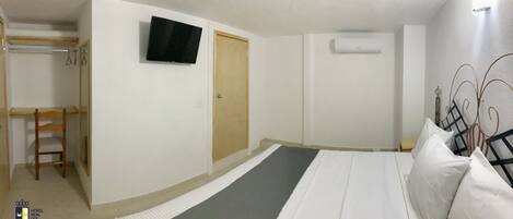 A bedroom with a bed, a TV, a wardrobe, and a door.