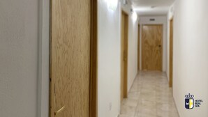 A hotel hallway with wooden doors and a tiled floor. - Hotel Real GDL (Guadalajara)