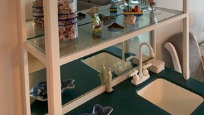 A glass display cabinet with decorative items and a mirror below it. - Luxury 5th Floor Oceanfront Condo next to Ritz Carlton! (Fernandina Beach)