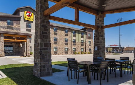 A hotel with a stone facade, outdoor seating area, and a visible parking lot.