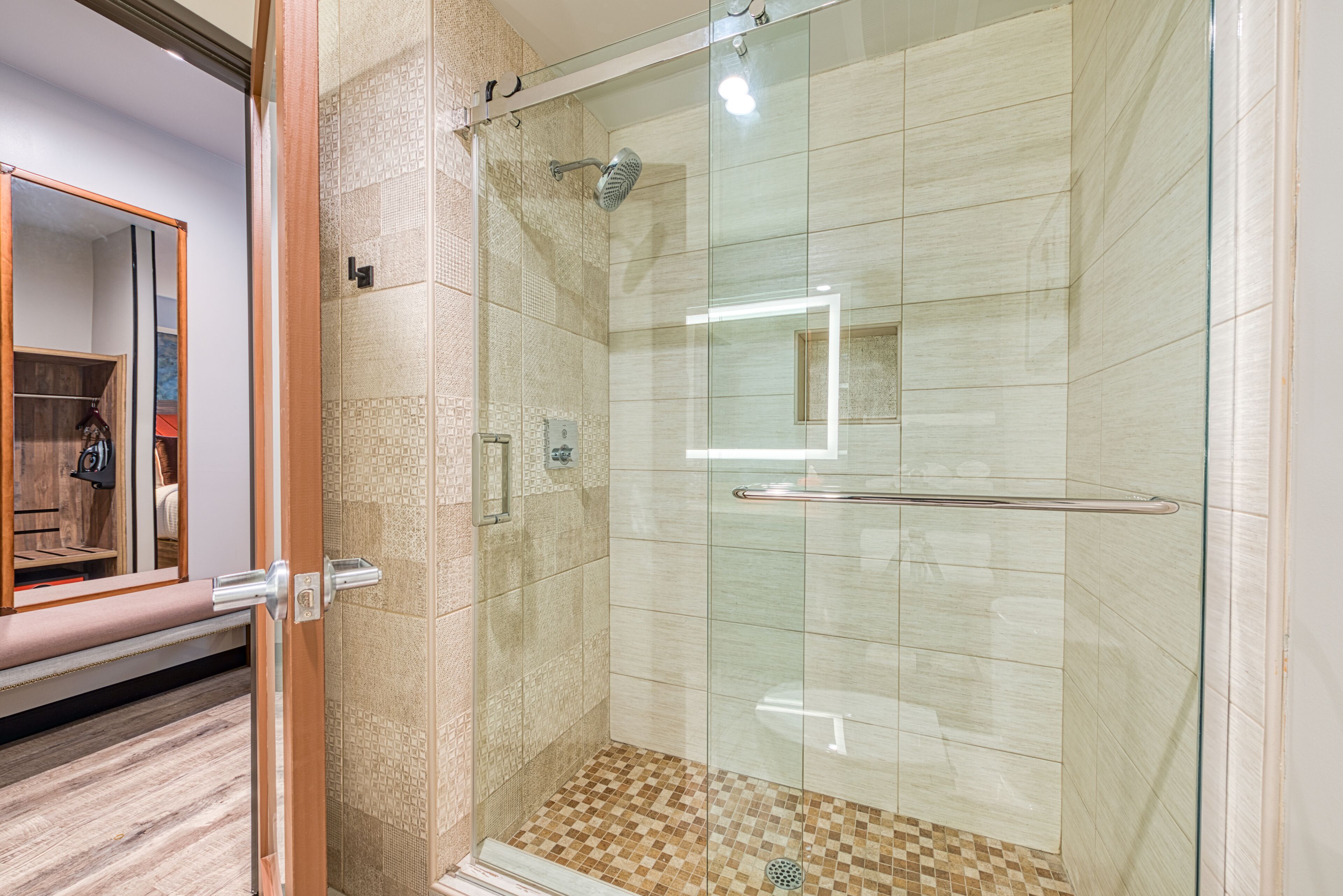 Ducha con paredes de vidrio, suelo de azulejos, barandilla y puerta de cristal.