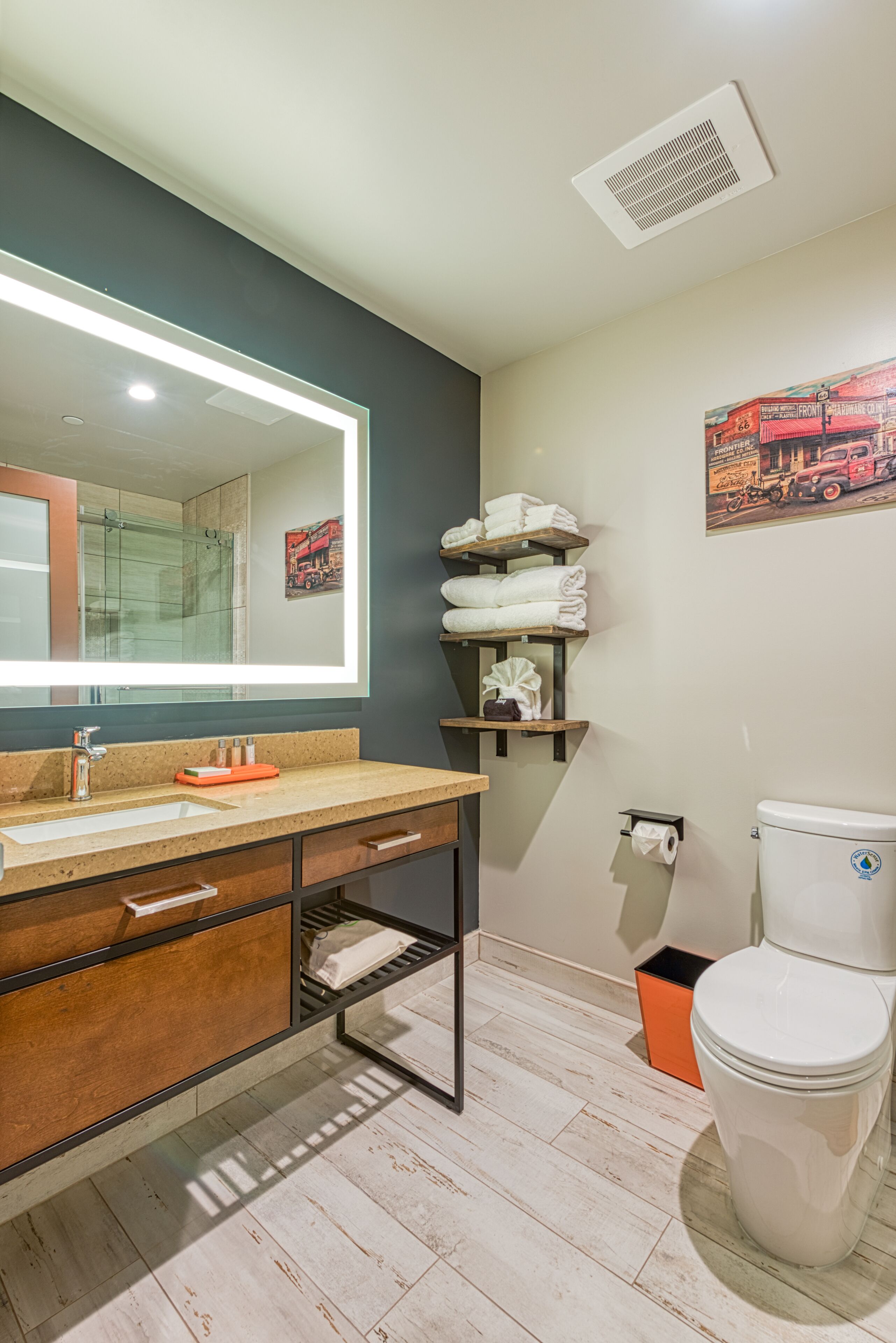 A modern bathroom with a large mirror, a sink with a faucet, a toilet, and a shower area.