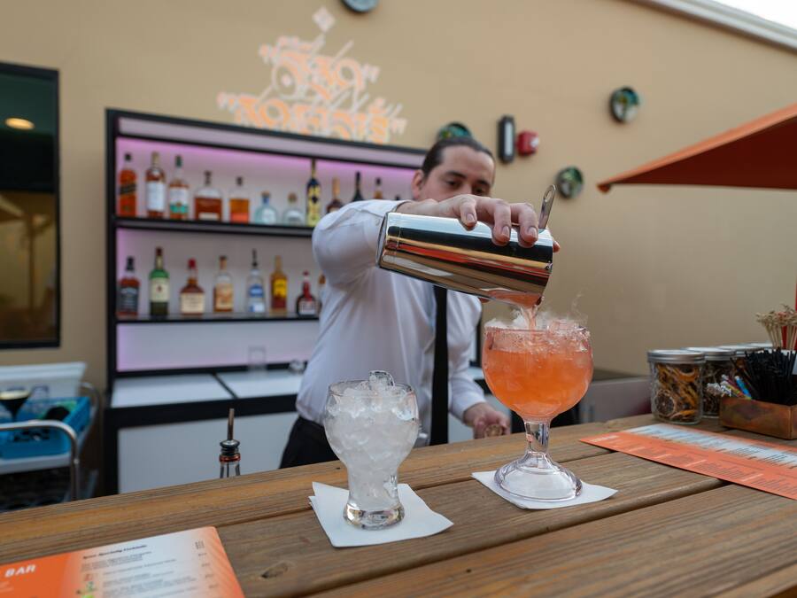 Un barman verse une boisson dans un verre au comptoir d’un bar.
