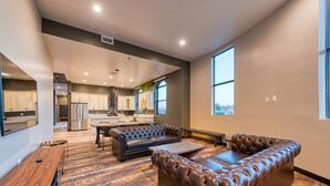 A modern living room with a leather sofa, a dining table, and a kitchen in the background. - Hotel Lexen Santa Clarita Valencia Near Six Flags (Newhall)