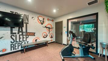Ein Fitnessstudio mit Trainingsgeräten, einer Bank und motivierenden Wandbildern.