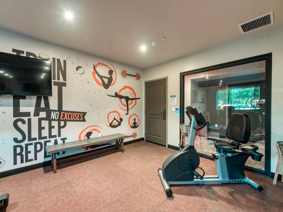 A gym with exercise equipment, a bench, and motivational wall art.