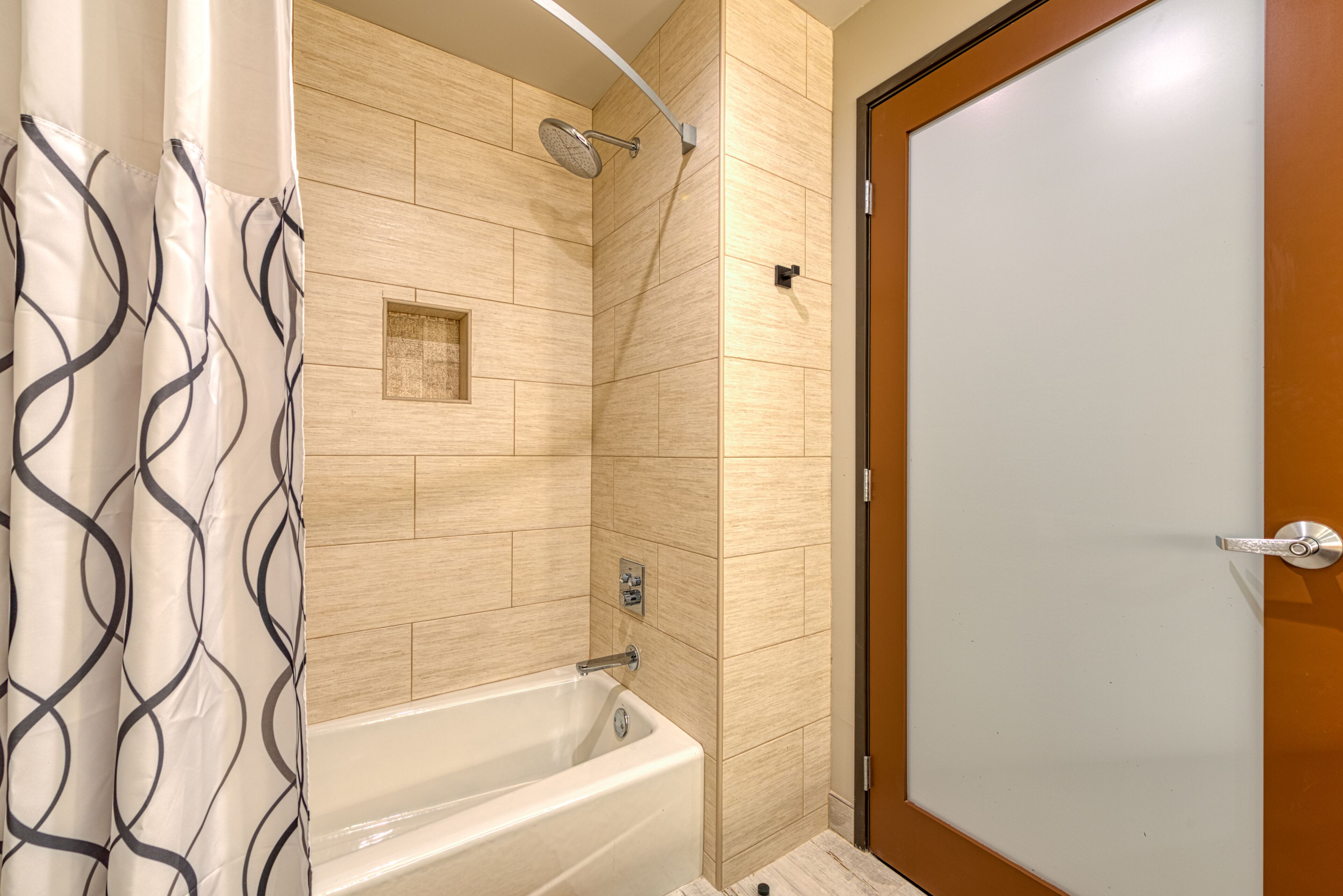 Ein modernes Badezimmer mit Badewanne, Dusche und einer Holztür.