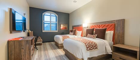 A modern bedroom with two beds, a desk, and a chair.