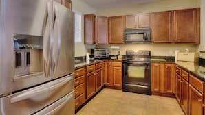 A kitchen with stainless steel appliances, wooden cabinets, and a tiled floor. - Lake Life Luxury on the Water (Bean Station)