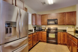 Enjoy cooking in this fully equipped kitchen with a refrigerator, microwave, oven, and cabinets.