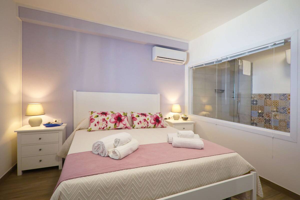 A neatly arranged bedroom with a bed, bedside tables, and a window.