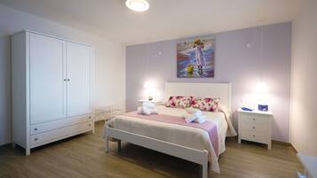A bedroom with a bed, a nightstand, a wardrobe, and a painting on the wall.