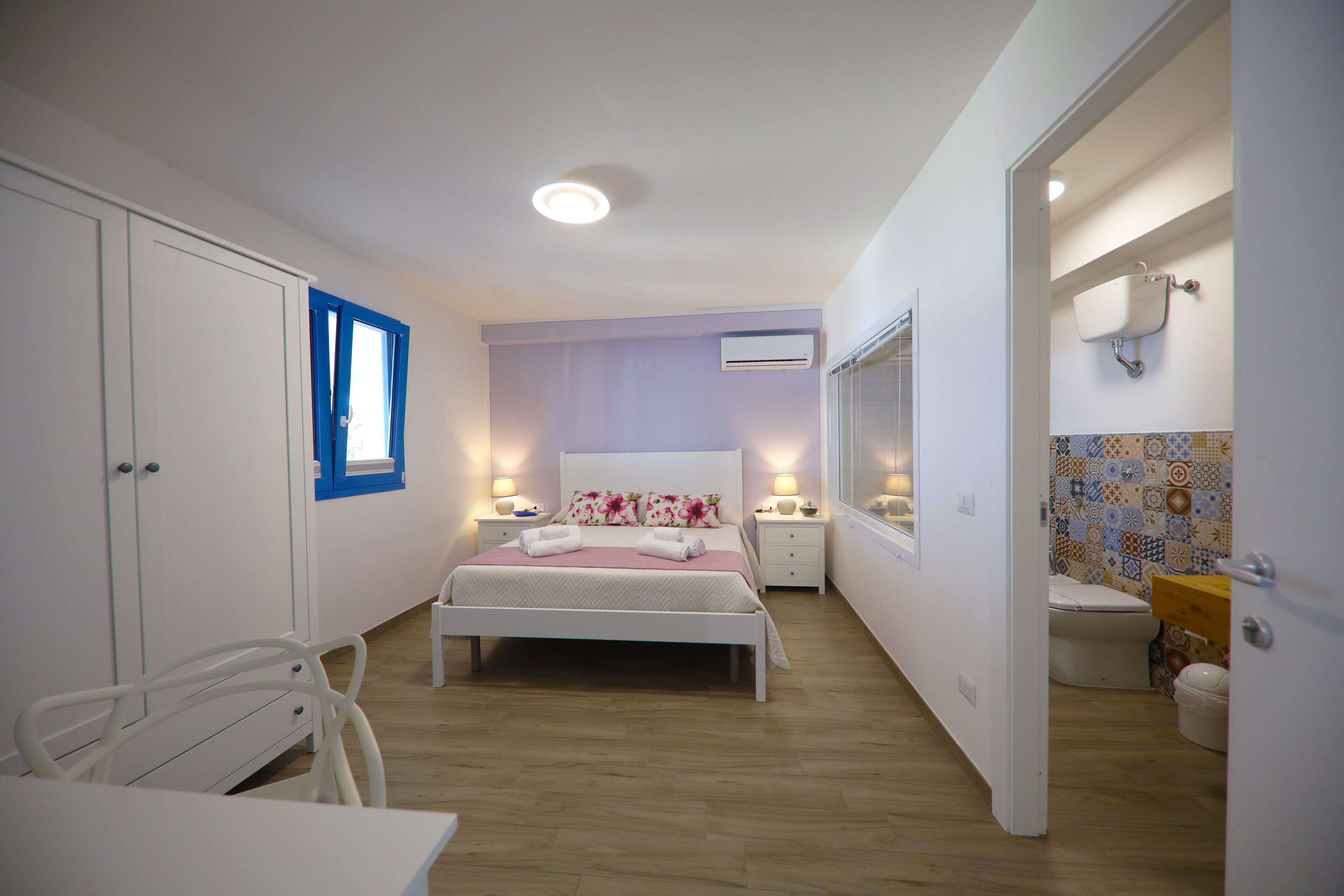 Un dormitorio con cama, mesitas de noche, armario y baño privado con inodoro y ducha.