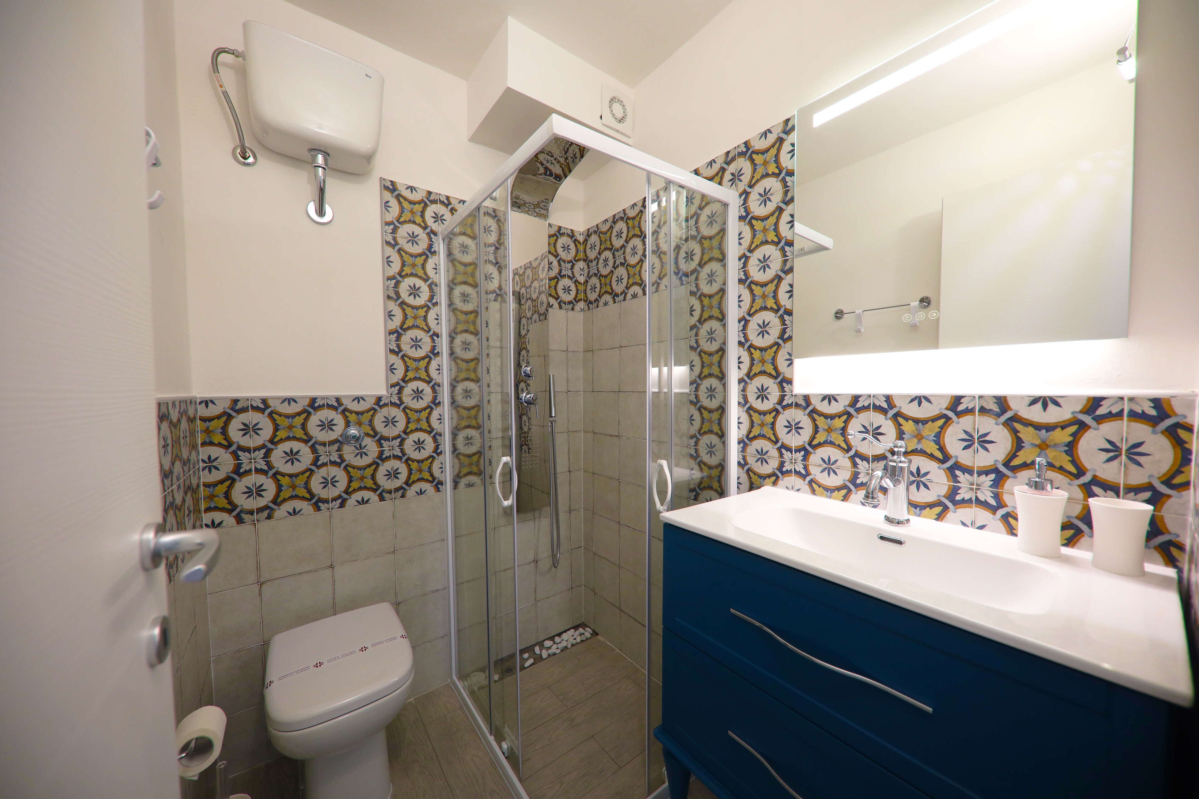 A bathroom with a toilet, a shower with glass doors, a sink, and a mirror.