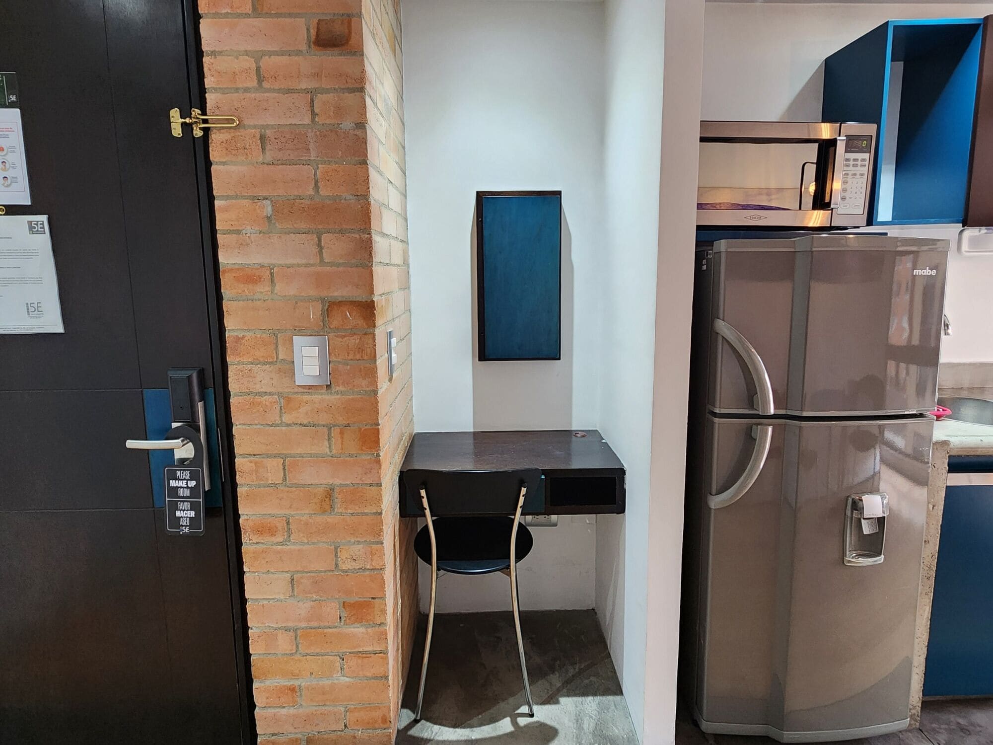 A compact kitchen with a refrigerator, a small table, and a chair.