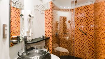 Un bagno moderno con doccia vetrata, lavabo nero con lavagna in vetro e water bianco.