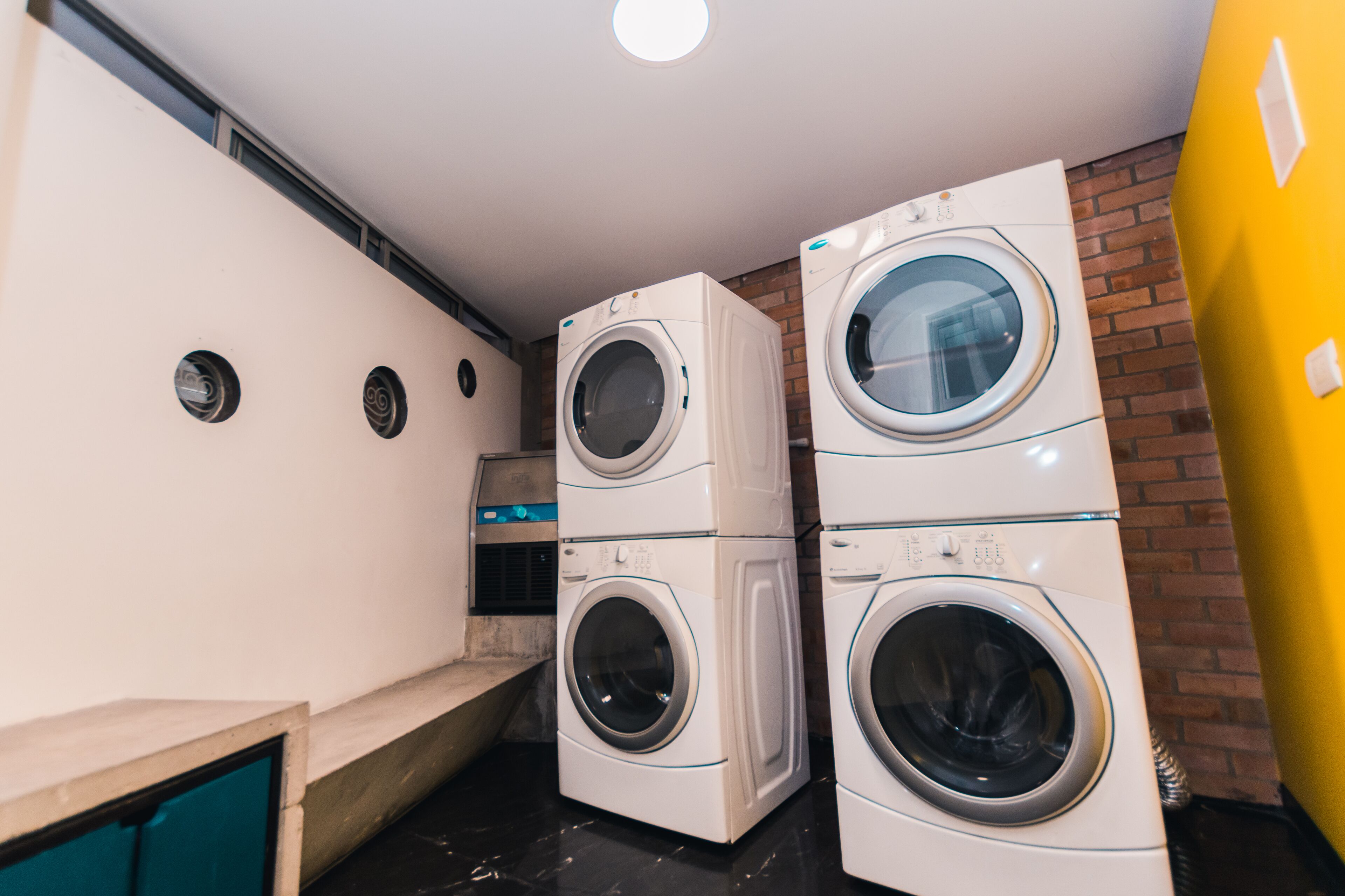 A laundry room with two stacked front-loading washing machines and a dryer.