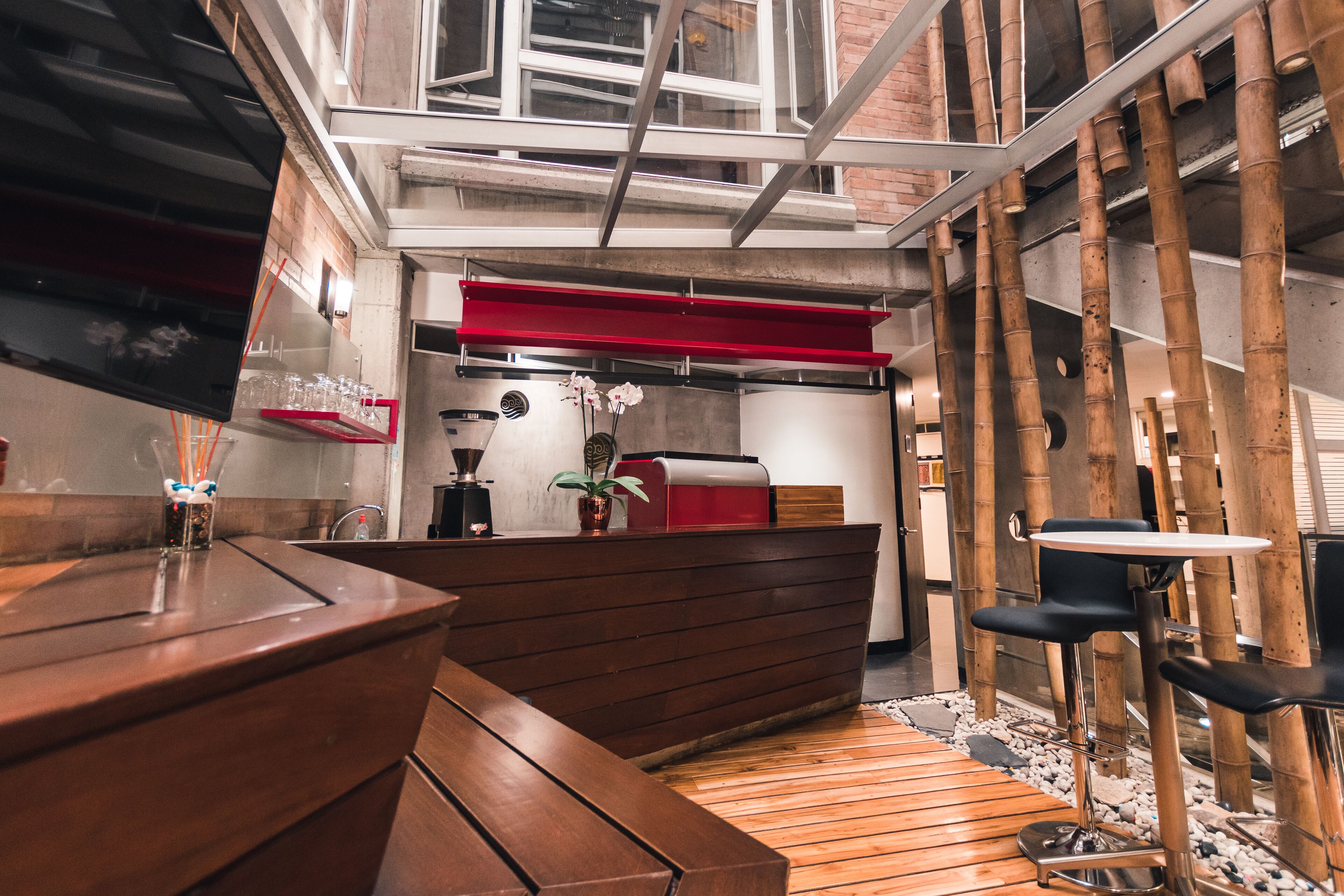 A modern interior with a wooden bench, a red counter, and a small table with two chairs.