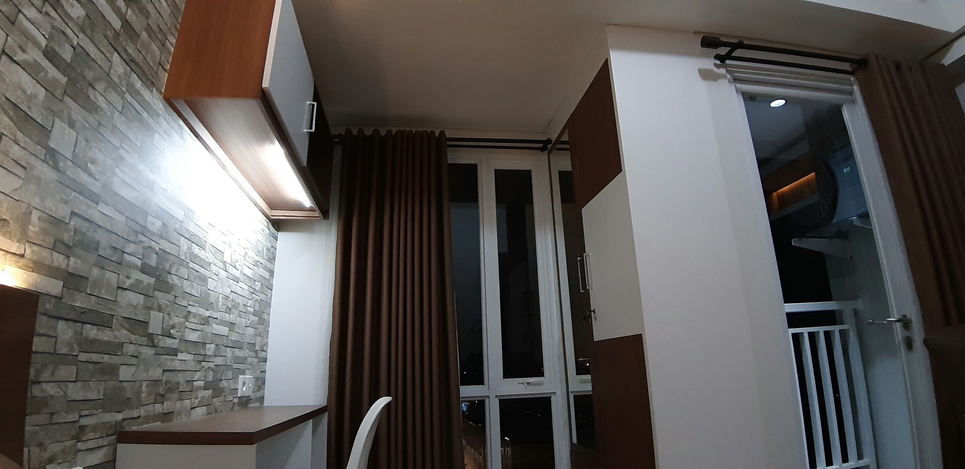 Une pièce avec un mur en pierre, une porte coulissante et un luminaire au plafond.