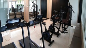 Un gimnasio moderno con diversas máquinas de cardio, un espejo grande y un ventanal.