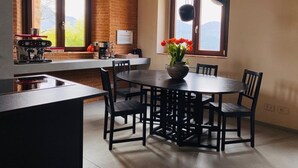 Una cocina moderna con comedor, que presenta una mesa redonda con sillas, una cafetera y vistas al exterior.