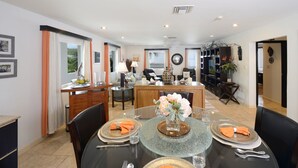 A modern dining area with a glass table set for four, surrounded by black chairs. - Condo SeaStar 24 (Oyster Pond)