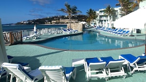 A pool area with lounge chairs and a view of the ocean. - Condo SeaStar 24 (Oyster Pond)
