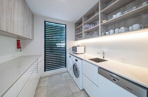 Eine moderne Küche mit integrierten Geräten, einer Waschmaschine und einem Regal mit Gläsern.