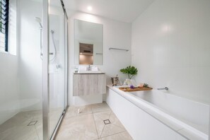 A modern bathroom with a glass shower enclosure, a white sink, and a bathtub.