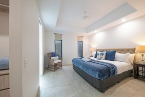 Ein Schlafzimmer mit einem großen Bett, einem Sessel und einem Nachttisch.
