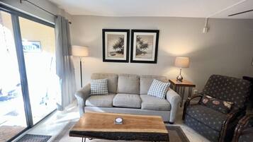 Relax in this inviting living space with a sofa, armchair, and floor lamp, offering a comfortable spot to unwind and take in the view.