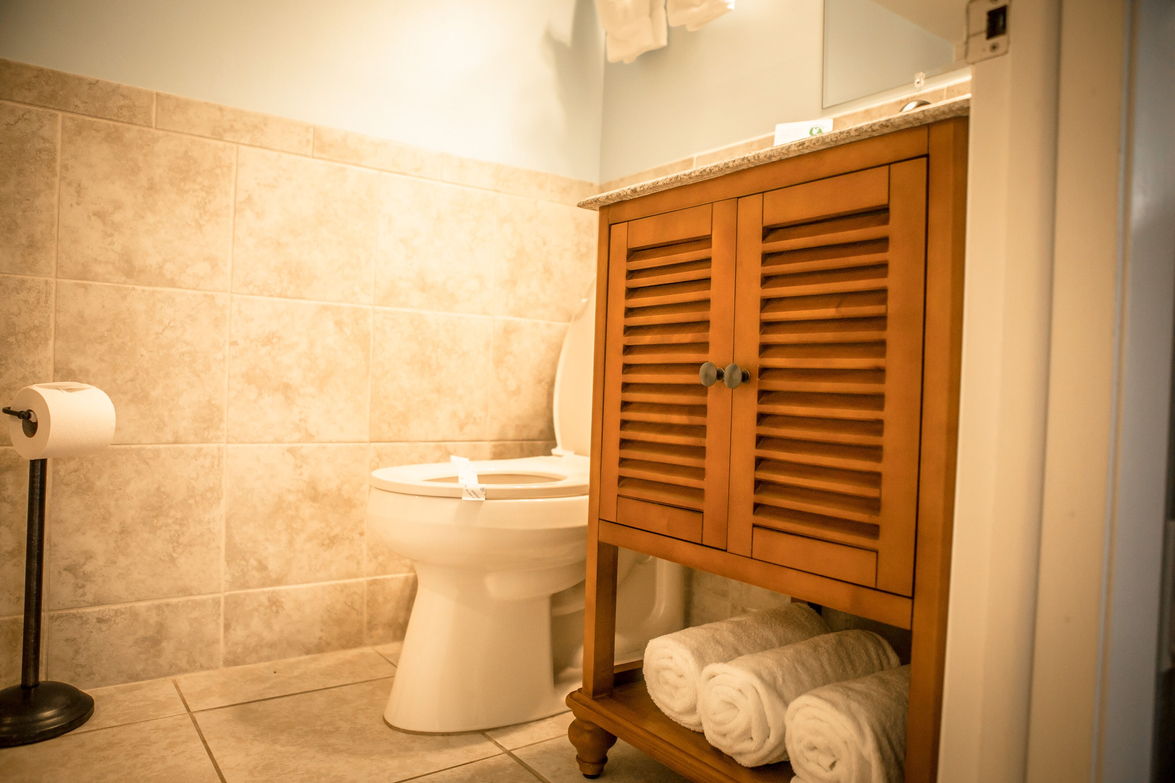 Une salle de bain comprenant des toilettes, un porte-serviettes avec des serviettes et un rouleau de papier toilette.