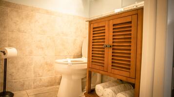 Une salle de bain comprenant des toilettes, un porte-serviettes avec des serviettes et un rouleau de papier toilette.