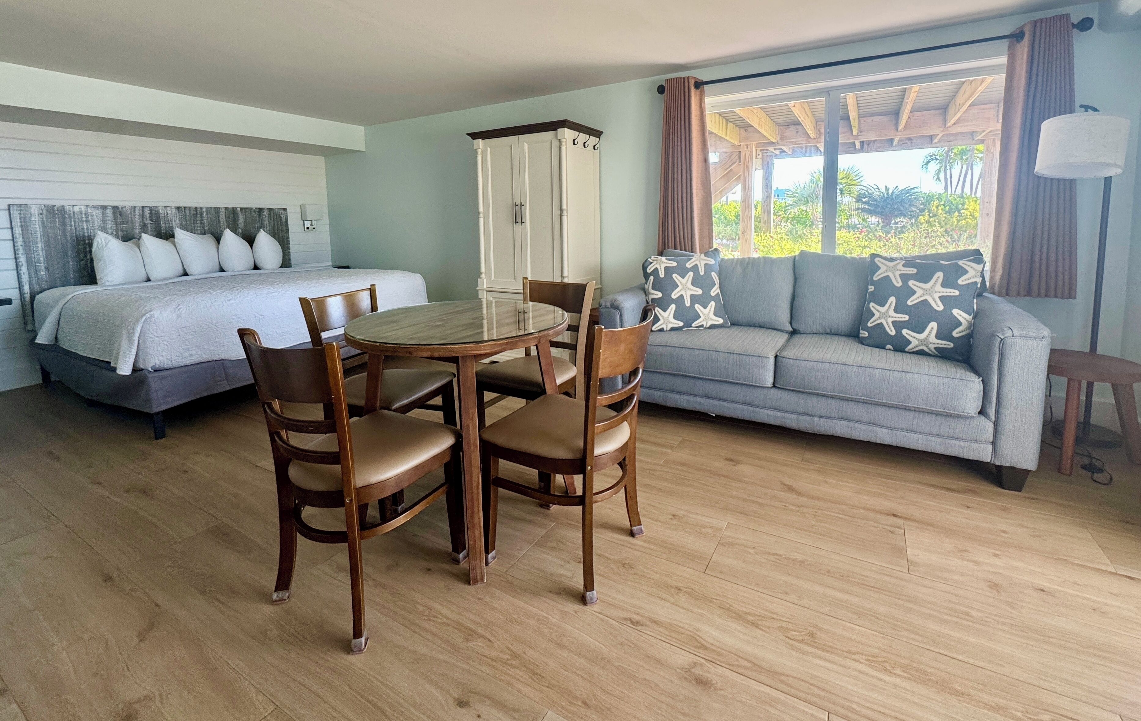 Une chambre à coucher avec un lit, une table à manger avec des chaises, un canapé et une armoire.
