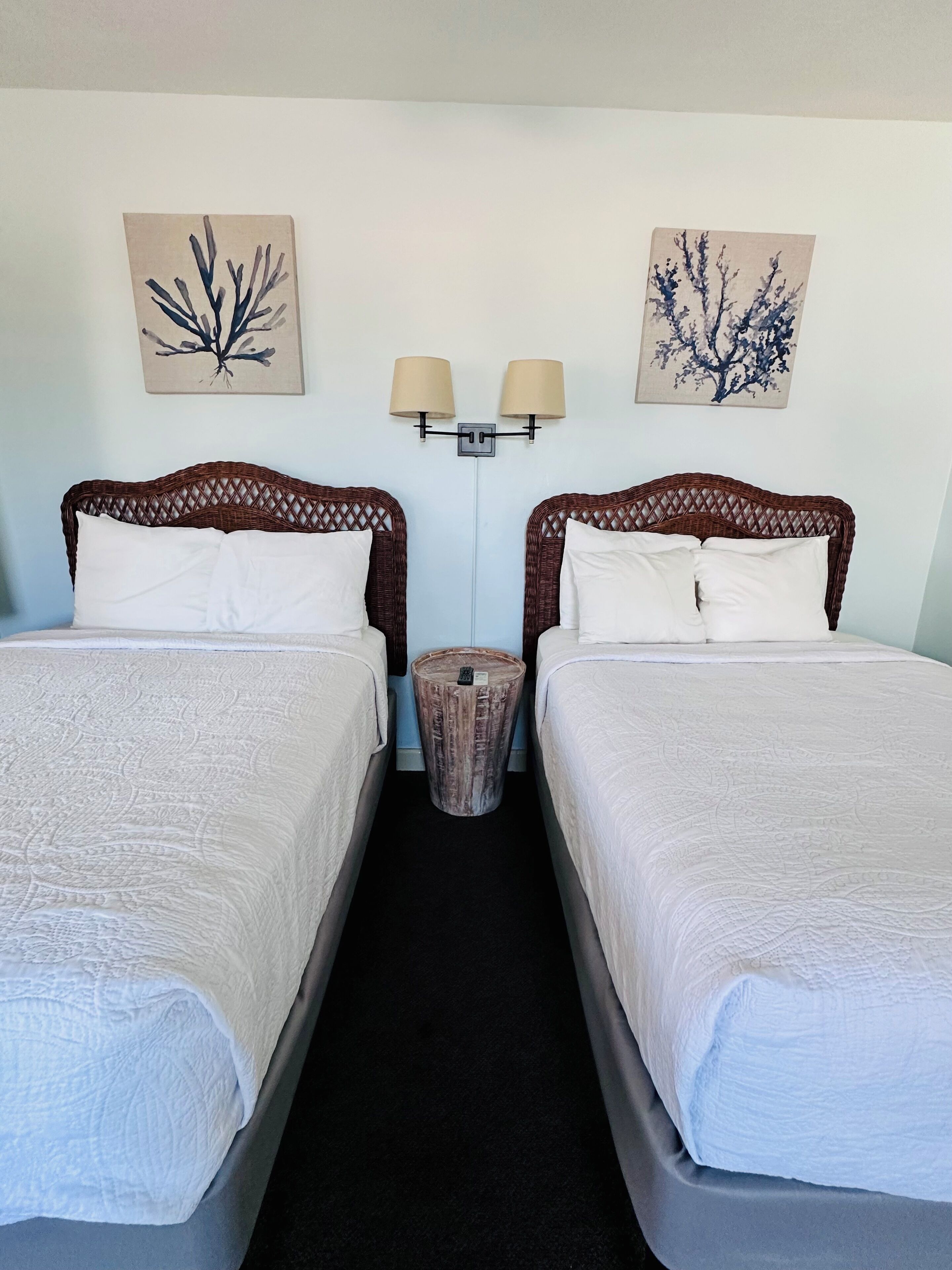 Une chambre d’hôtel avec deux lits, une petite table ronde et des lampes fixées au mur.