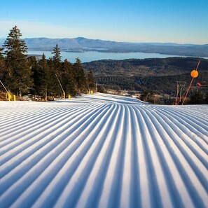 A snow-covered ski slope with a view of mountains and a lake in the distance. - Winnisquam Lake House (Tilton)
