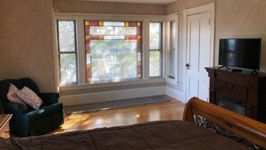 Une chambre à coucher avec un lit, une chaise, une télévision et une cheminée.