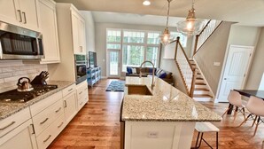 A kitchen with granite countertops, white cabinetry, a built-in oven, and a large island with a sink. - Coastal Club * 6BR Lewes Beach House (Lewes)