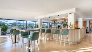 A spacious bar area with a high ceiling, large windows offering a view of the mountains, and a bar counter with stools. - Premium 2-Bed Villa | Quinta do Lago | Sleeps 6 (Almancil)