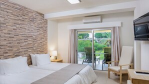A hotel room with a large bed, a desk, a chair, a TV, and a view of the outdoors through a sliding door. - Premium 2-Bed Villa | Quinta do Lago | Sleeps 6 (Almancil)