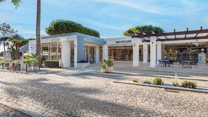 A modern building with "NOA" signage, a reception area, and outdoor seating. - Premium 2-Bed Villa | Quinta do Lago | Sleeps 6 (Almancil)