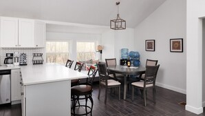 Una cocina moderna con armarios blancos, una isla central y un comedor con sillas y una mesa.