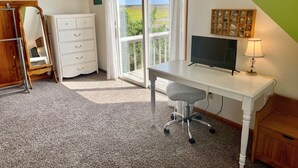 A bedroom with a desk, a mirror, a dresser, and a window with a view of greenery. - JD36: Flyway | Multiple Decks with Amazing Marsh Views (Ocracoke)