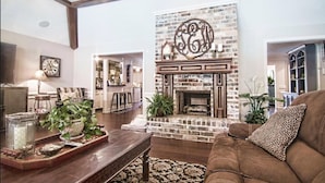 A living room with a fireplace, a couch, and a coffee table. - Houston Hidden Oasis (Spring)