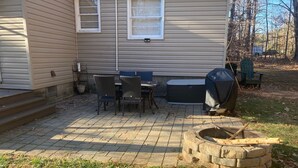 Un patio con una fogata, muebles de exterior y una parrilla.